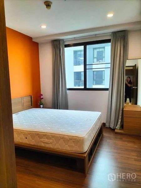 Condominium for rent in Watthana, Bangkok - Bedroom with large window, curtains, wooden floor and dressing area.