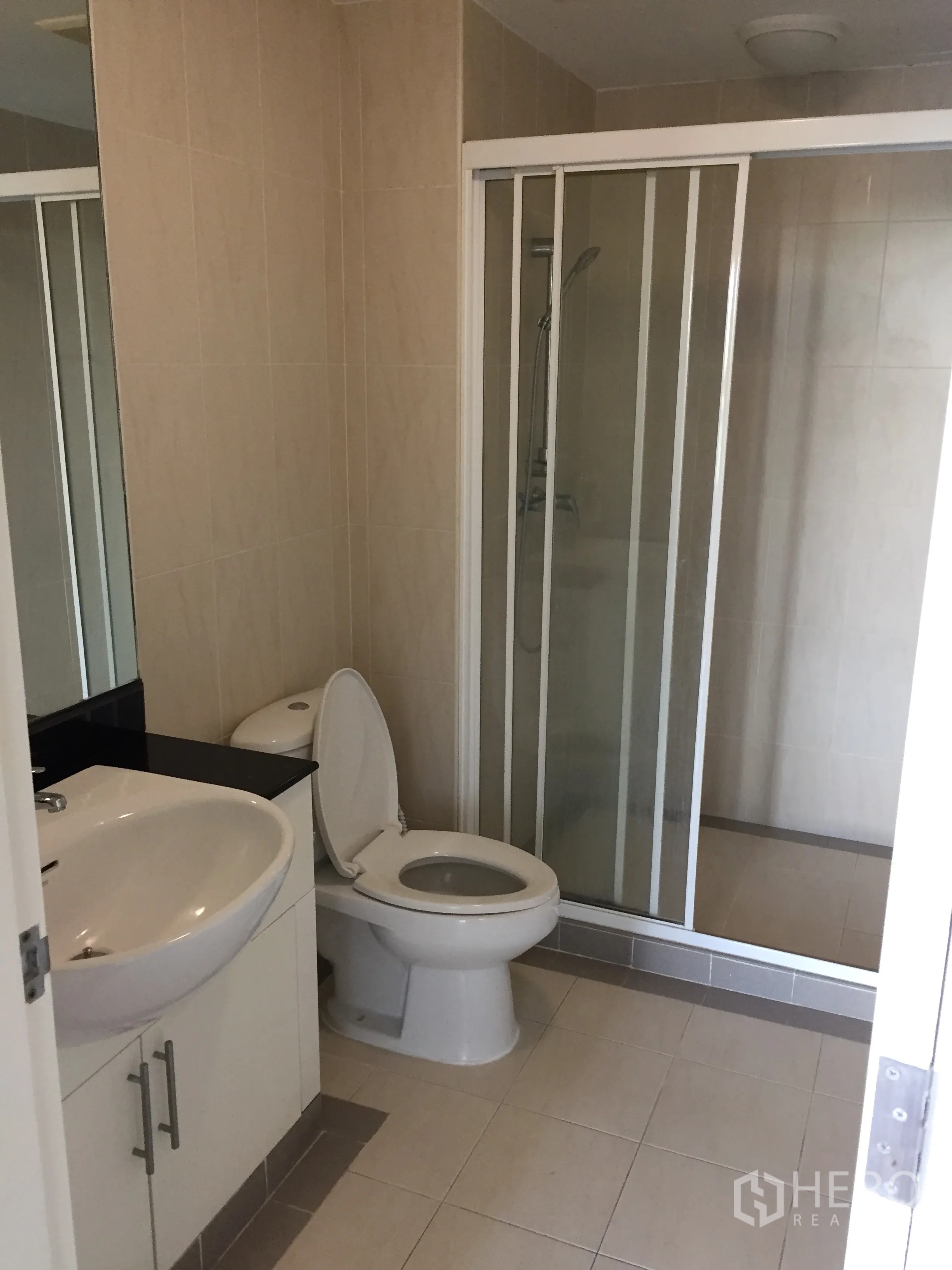 Condominium for rent in Watthana, Bangkok - Tiled bathroom with vanity, toilet and glass-enclosed shower.