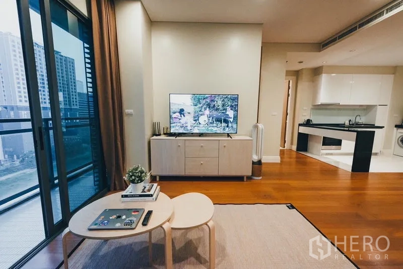 Condominium for rent in Khlong Toei, Bangkok - Living area beside balcony with nesting coffee tables and TV console.