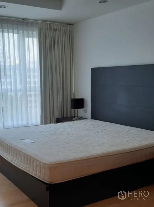公寓 出租在Watthana, Bangkok - 宽敞主卧，落地窗帘与充足自然采光的大床。