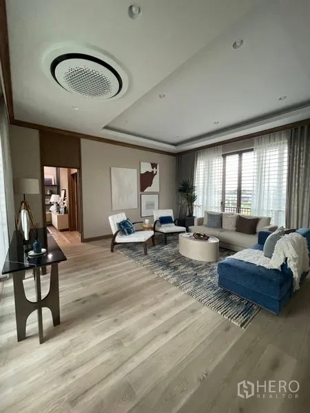 Detached House for sale in Bang Kapi, Bangkok - Spacious family lounge with wood flooring, balcony doors and a modern ceiling light.