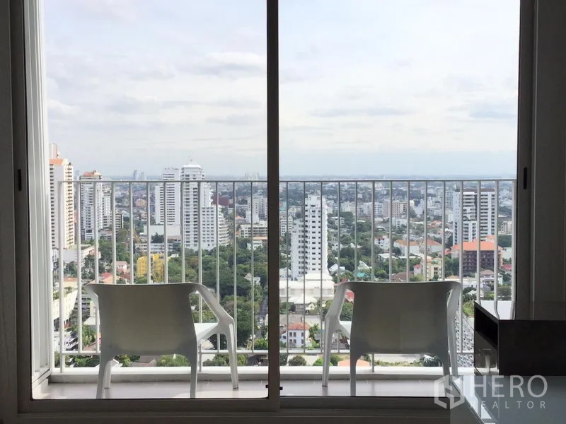 公寓 出租或出售在Watthana, Bangkok - 阳台配两把椅子，远眺瓦他那区城市全景。