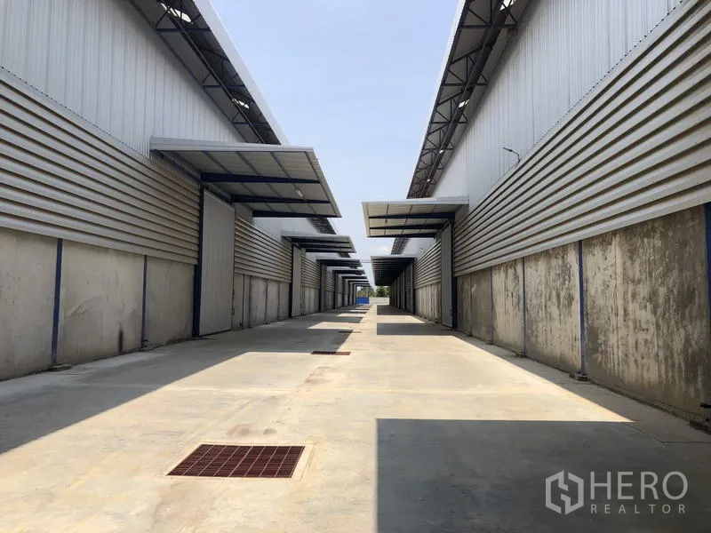 Factory for rent in Lat Lum Kaeo, Pathum Thani - Service lane between warehouse blocks with canopies and drainage grates.
