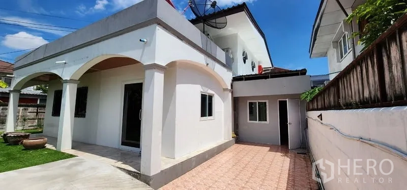 独立式住宅 出租在Lat Phrao, Bangkok - 房屋侧立面，拱形露台与宽阔铺砖停车区。