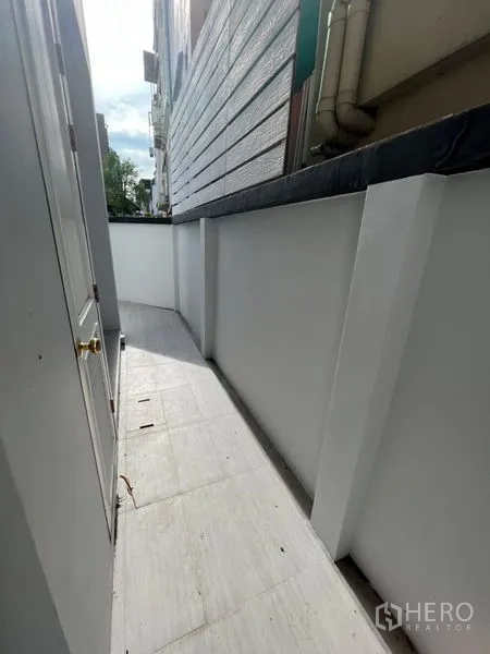 带办公室的家 出租或出售在Watthana, Bangkok - 房屋侧边狭长步道，白墙与瓷砖地面。