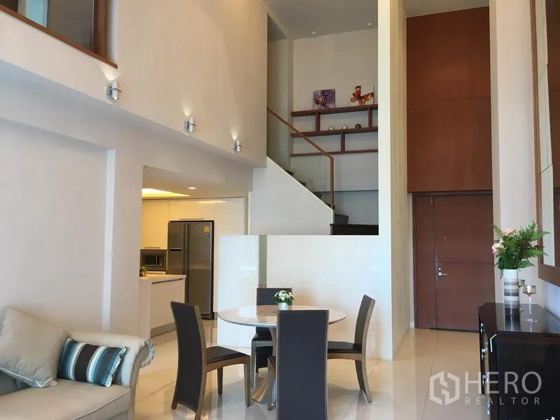 คอนโด ให้เช่าในPathum Wan, Bangkok - ห้องนั่งเล่นเพดานสูงพร้อมบันไดสู่ชั้นลอย ครัวแบบเปิดและชุดโต๊ะอาหาร