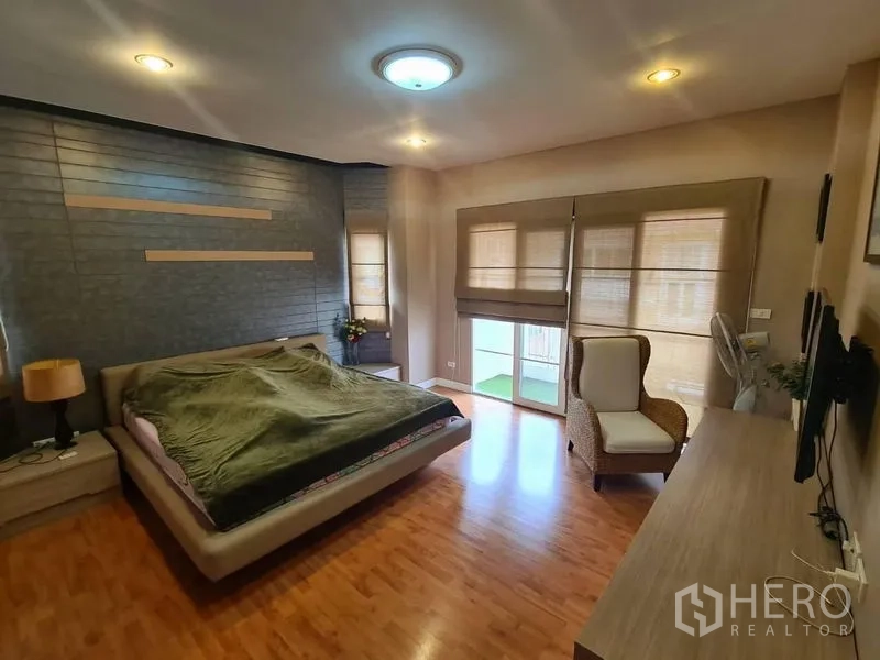 Detached House for rent in Sai Mai, Bangkok - Large master bedroom with wood floors, balcony doors and a feature wall.