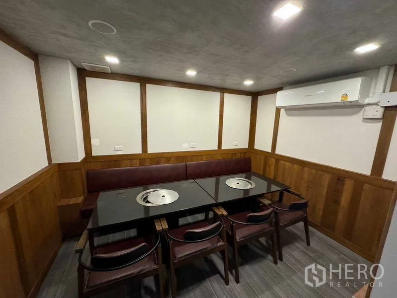 Shophouse for rent in Watthana, Bangkok - Private dining room with built-in bench, two grill tables and wall-mounted air conditioner.