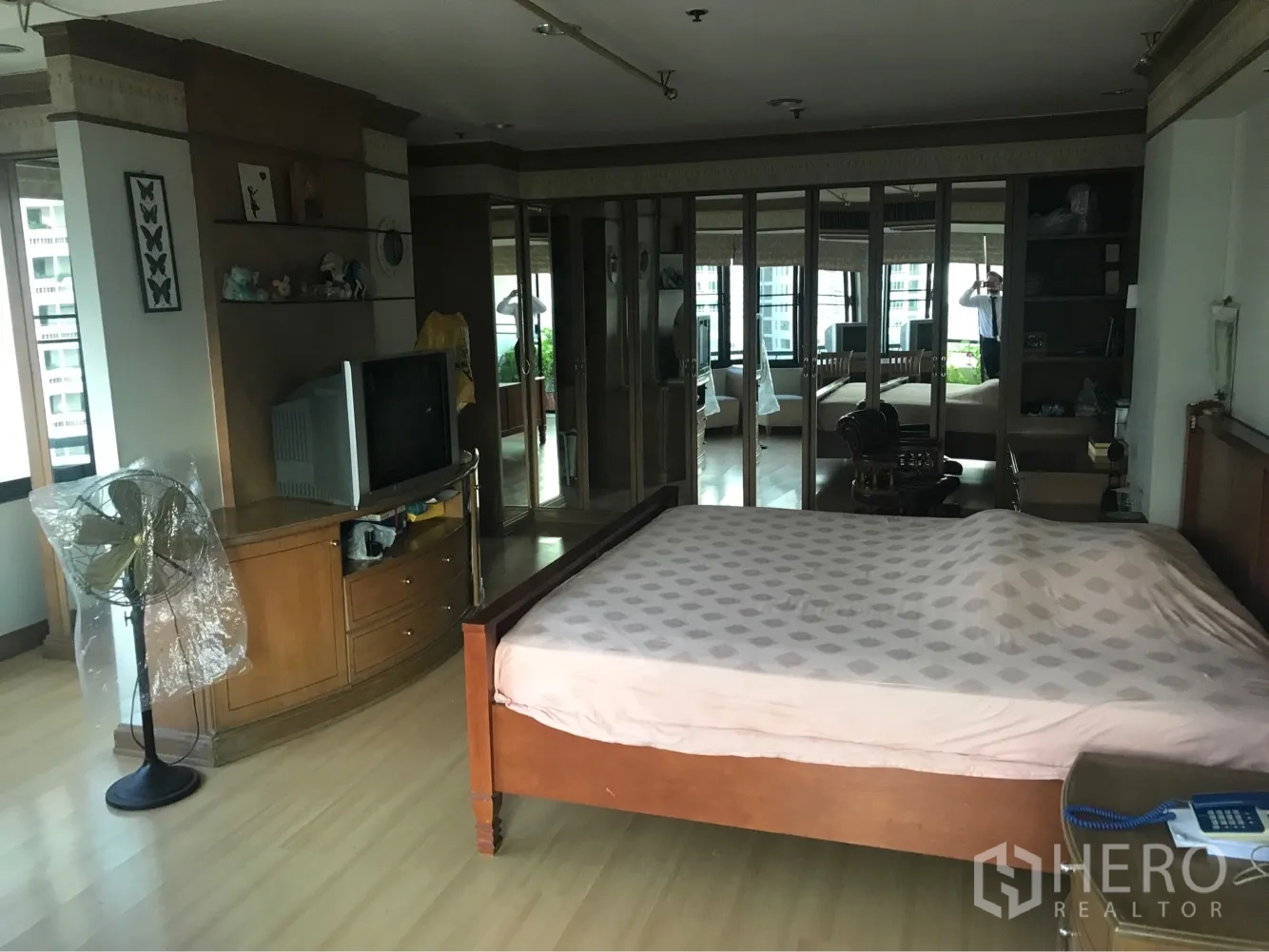 Condominium for rent or sale in Watthana, Bangkok - Large master bedroom with a wooden bed, mirrored wardrobes, and expansive windows.