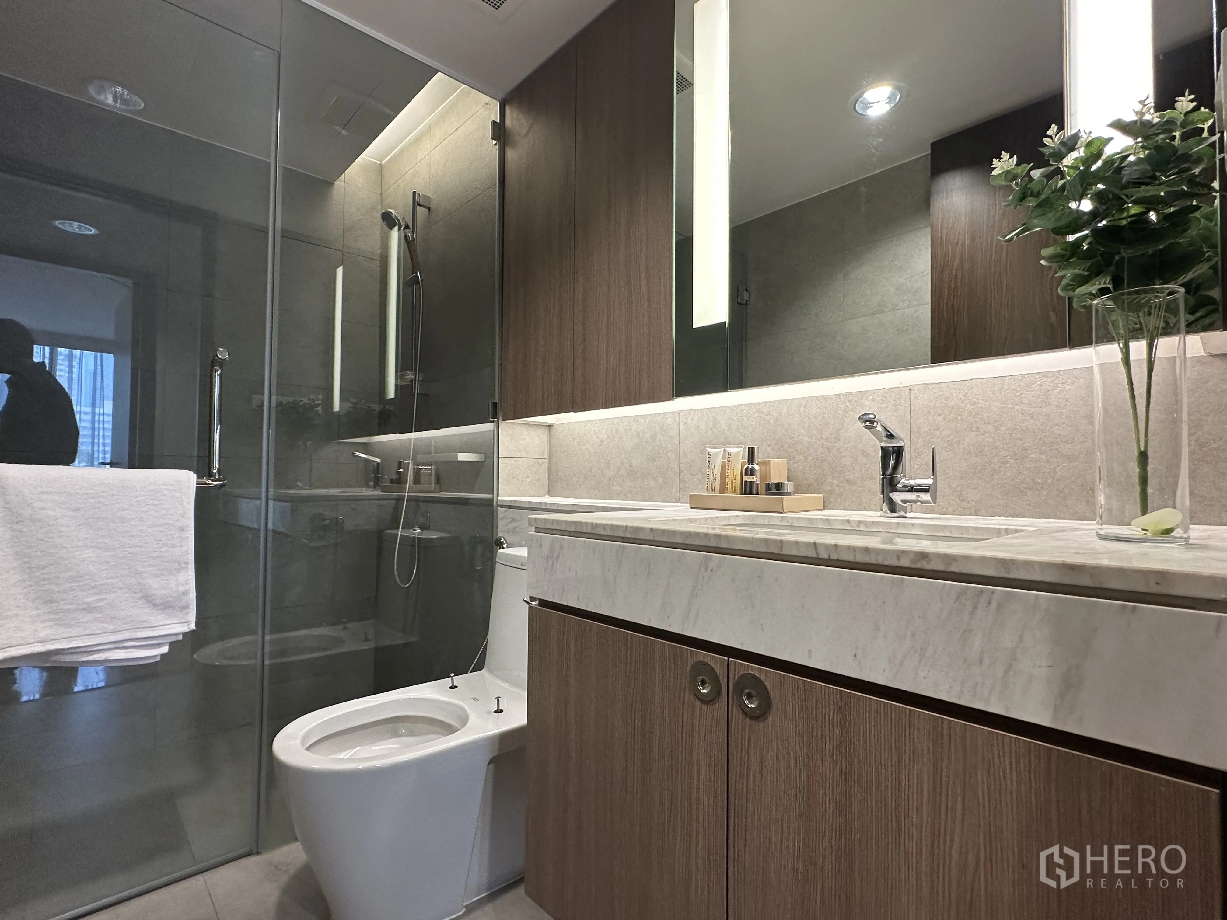 Condominium for rent in Khlong Toei, Bangkok - Sleek bathroom with glass-enclosed shower and marble countertop vanity.