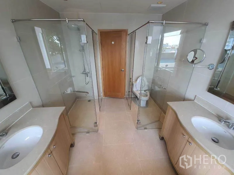 Condominium for rent or sale in Sathon, Bangkok - Large bathroom with twin vanities and separate glass-enclosed showers on both sides.