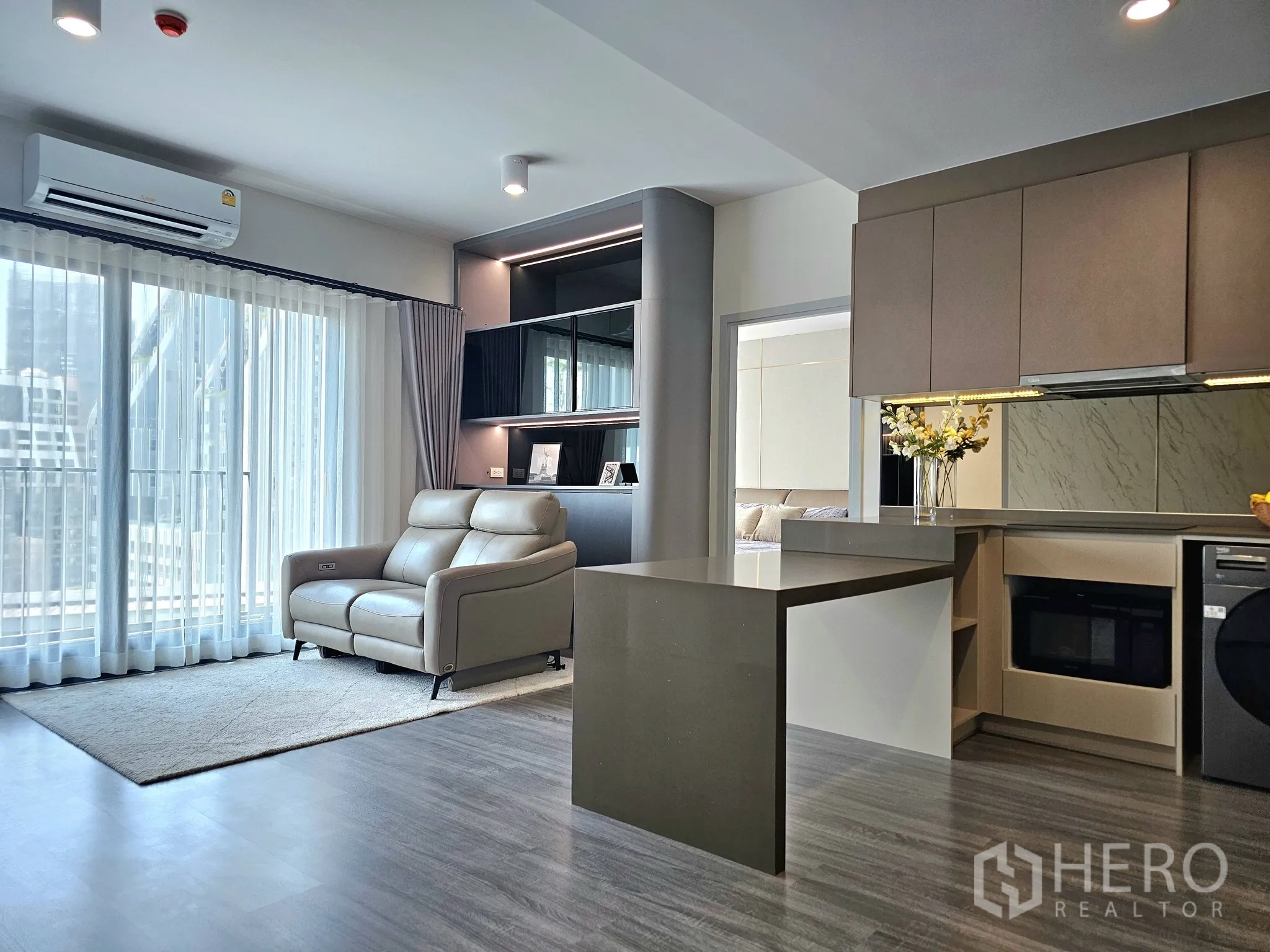公寓 for sale in Bang Rak, Bangkok - 通透明亮的客厅，大窗与浅色地毯，旁接厨房吧台。