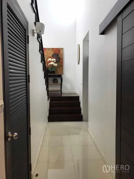Detached House for sale in Wang Thonglang, Bangkok - Entrance corridor with staircase, tiled floor and a console table with flowers