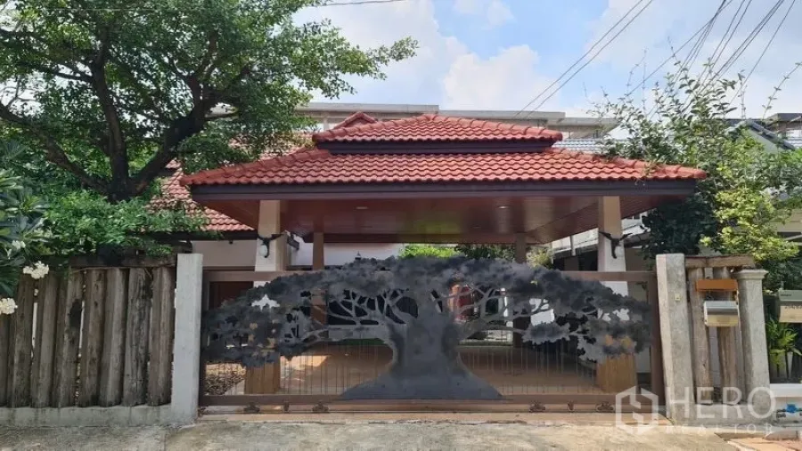 Detached House for rent in Saphan Sung, Bangkok - Thai-style entrance with red tiled roof and decorative tree-pattern metal gate of a detached house in Saphan Sung, Bangkok.