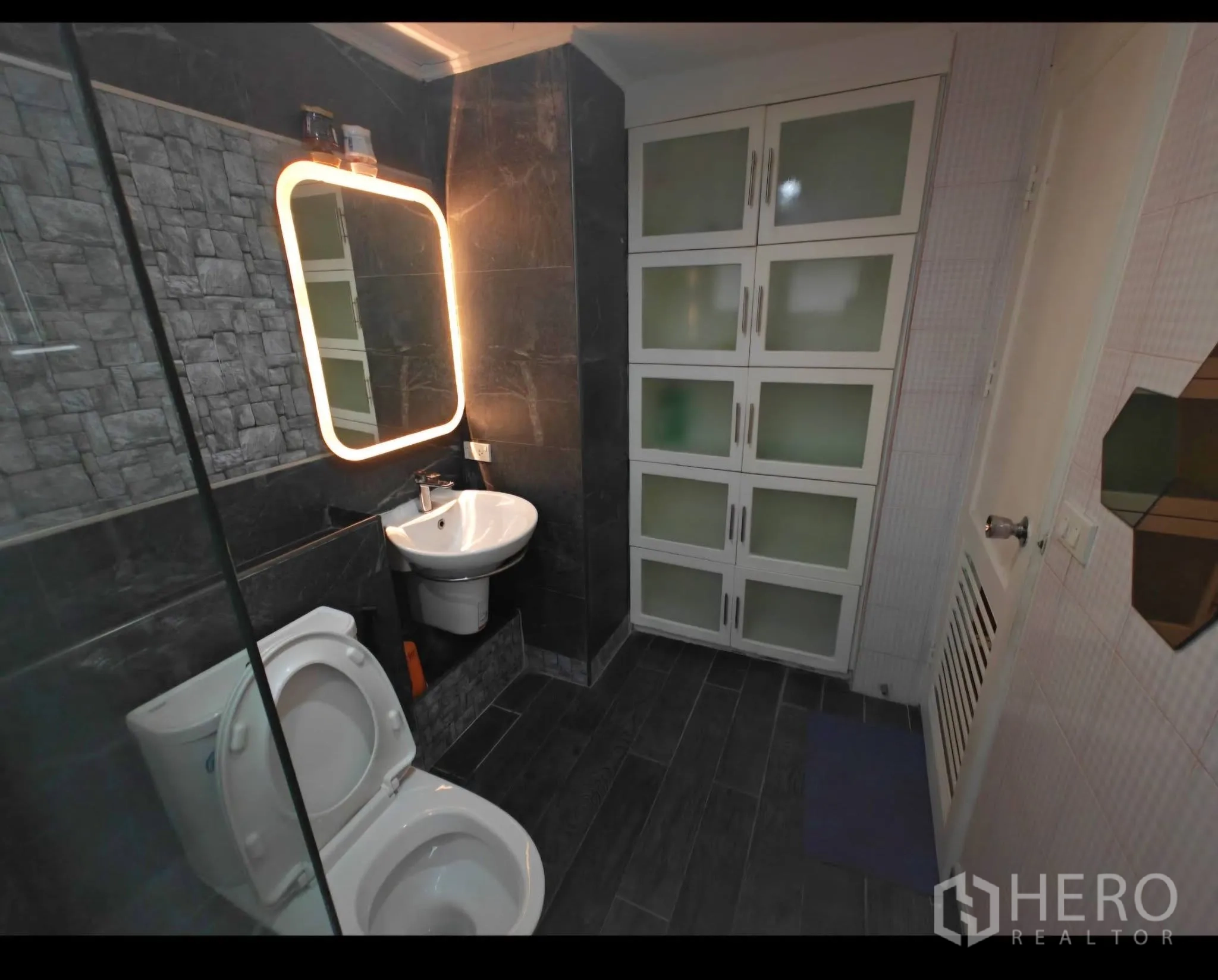公寓 for rent in Sathon, Bangkok - 现代卫浴配仿石墙砖、背光镜、玻璃淋浴隔屏与收纳柜。