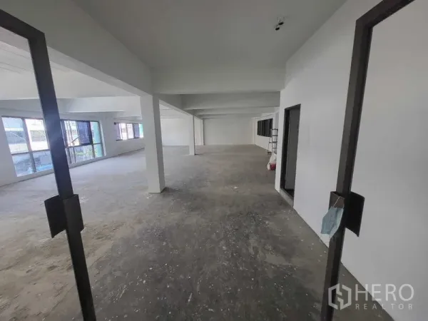 Factory for rent or sale in Samut Prakan - Open-plan upper floor office space with large windows and white columns.