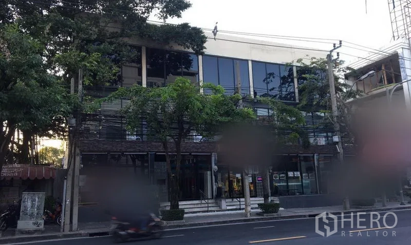 Retail Space for rent in Watthana, Bangkok - Street-facing retail building with wide glass windows and trees along Ekkamai in Bangkok.