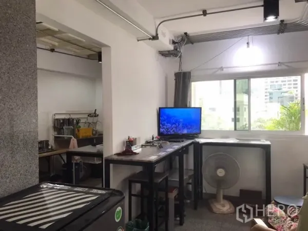Condominium for rent in Phaya Thai, Bangkok - Window-side nook with bar-height tables, TV and a glimpse of a utility kitchen in a Bangkok condominium.