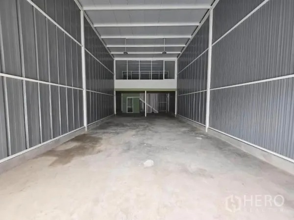 货栈 出租在Prawet, Bangkok - 高挑仓库内部，混凝土地面，尽头为夹层办公室与楼梯。