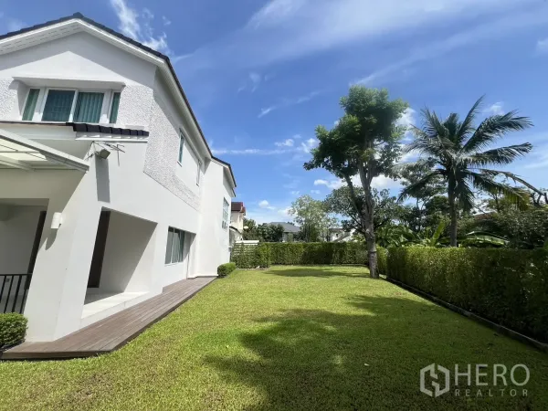 Detached House for rent in Mueang Samut Prakan, Samut Prakan - Side garden with neat lawn, trees and tall hedges next to the house.