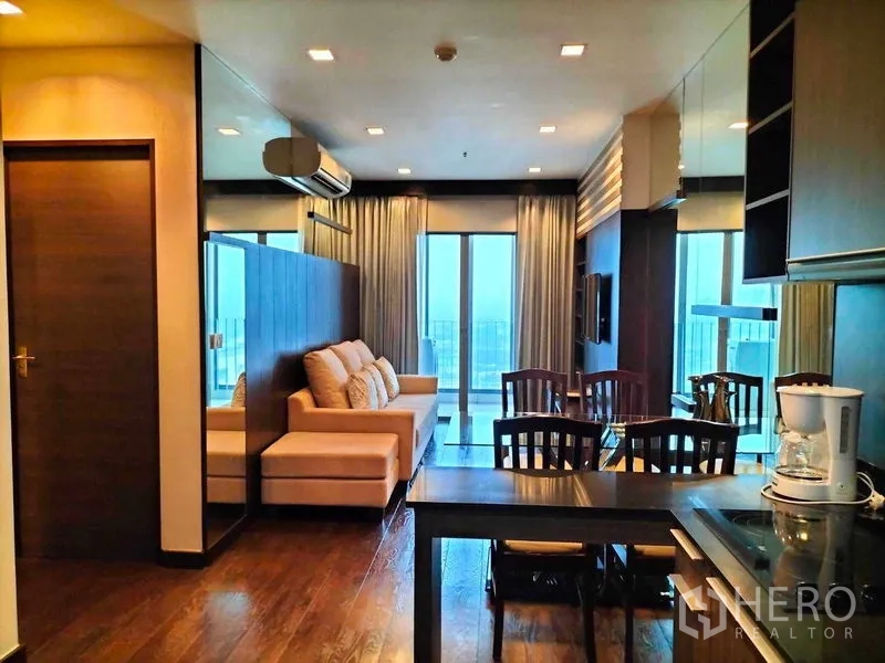 Condominium for rent in Ratchathewi, Bangkok - Open-plan living and dining room with sofa, dining set and balcony doors.