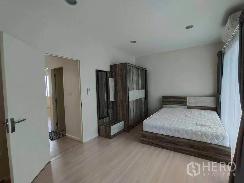 联排别墅 出租在Wang Thonglang, Bangkok - 卧室配木质床架、衣柜，门通向走廊。