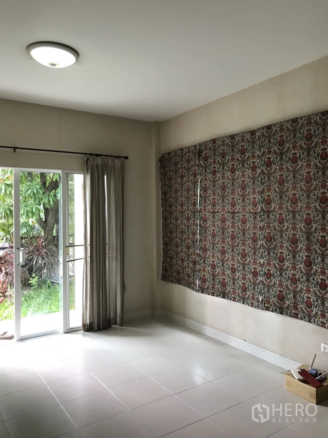 Detached House for rent in Lat Krabang, Bangkok - Bright living room with white tile floors, sliding glass doors and curtains opening to a green garden.