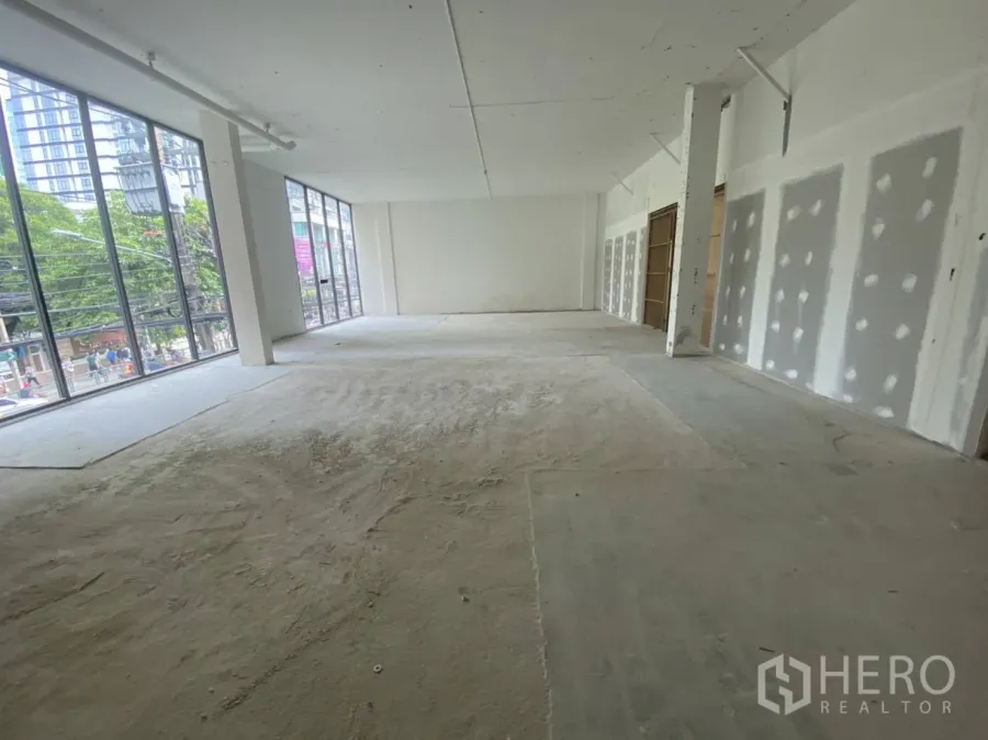 Retail Space for rent - Open-plan retail shell with high ceiling, concrete floor, and full-height windows offering street visibility and natural light.