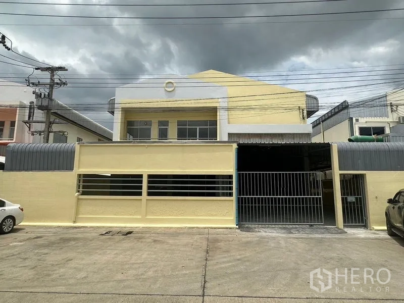 Factory for rent in Pathum Thani - Yellow factory facade with secure steel gate and parking apron.