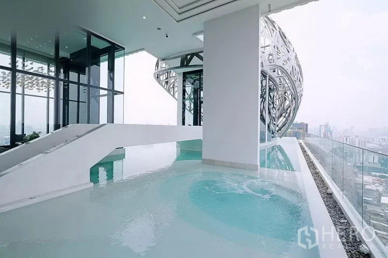 Condominium for rent in Watthana, Bangkok - Rooftop infinity pool with city skyline views beside a sculptural metal facade.