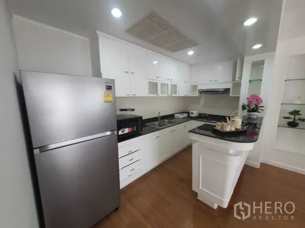 房间 出租在Watthana, Bangkok - 现代白色U形厨房，配不锈钢冰箱与黑色台面