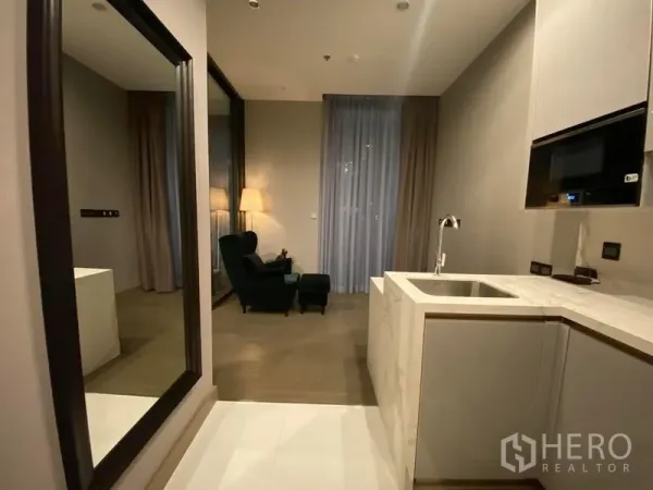 公寓 出租在Huai Khwang, Bangkok - 开放式客厅，带大理石L形厨房、落地镜与窗边休闲椅。