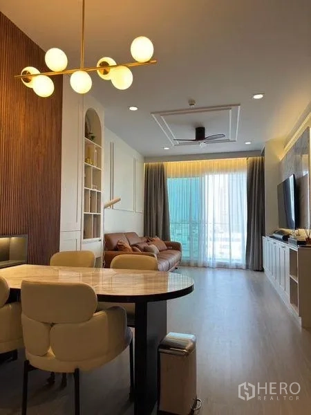 Condominium for rent in Bang Rak, Bangkok - Dining area and living room with globe chandelier, round table, built-in cabinetry and sliding balcony doors.