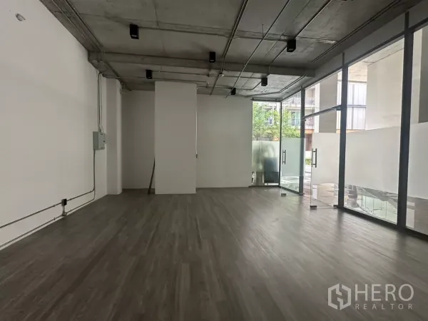 Retail Space for rent - Corner view of the shop showing full-height glass doors to the atrium, natural light and vinyl floors.