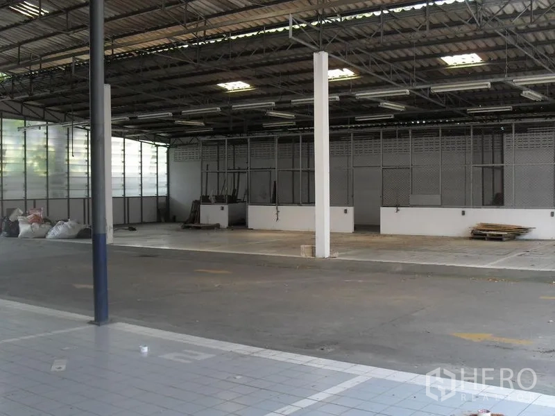 Retail Space for rent in Khlong Toei, Bangkok - Covered warehouse-style area with high metal roof, fluorescent lights and open concrete floor.