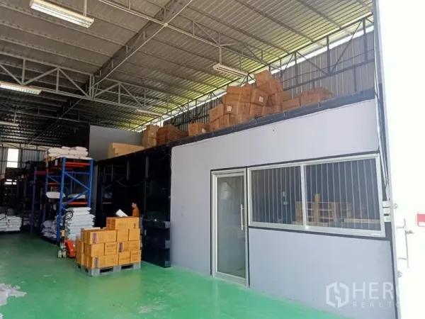 คลังสินค้า ให้เช่าในBang Kapi, Bangkok - มุมใกล้ของสำนักงานชั้นลอยพร้อมหน้าต่าง ภายในโกดังที่มีกล่องและชั้นวางของใต้หลังคาเมทัลชีท