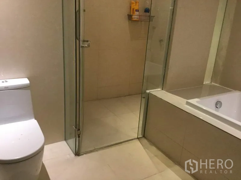 คอนโด ให้เช่าในWatthana, Bangkok - ห้องน้ำที่สองพร้อมห้องอาบน้ำกระจกใส อ่างอาบน้ำ และโถสุขภัณฑ์ โทนกระเบื้องสีอ่อน
