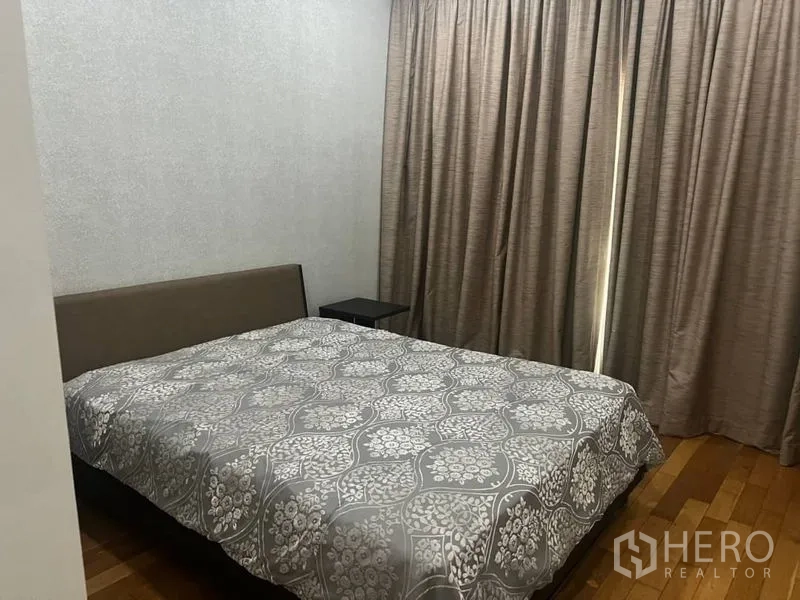 公寓 出租在Bangkok - 起居室黑色皮沙发面向电视柜，长窗帘与亮面地板。