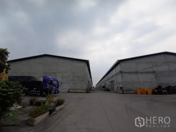 Warehouse for rent in Mueang Pathum Thani, Pathum Thani - Rows of warehouse buildings with an internal concrete road in an industrial compound.