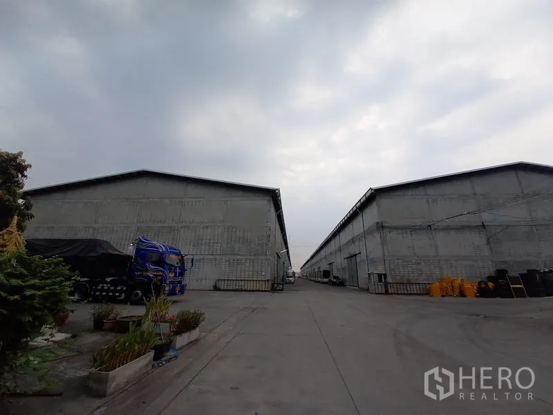 Warehouse for rent in Mueang Pathum Thani, Pathum Thani - Rows of warehouse buildings with an internal concrete road in an industrial compound.