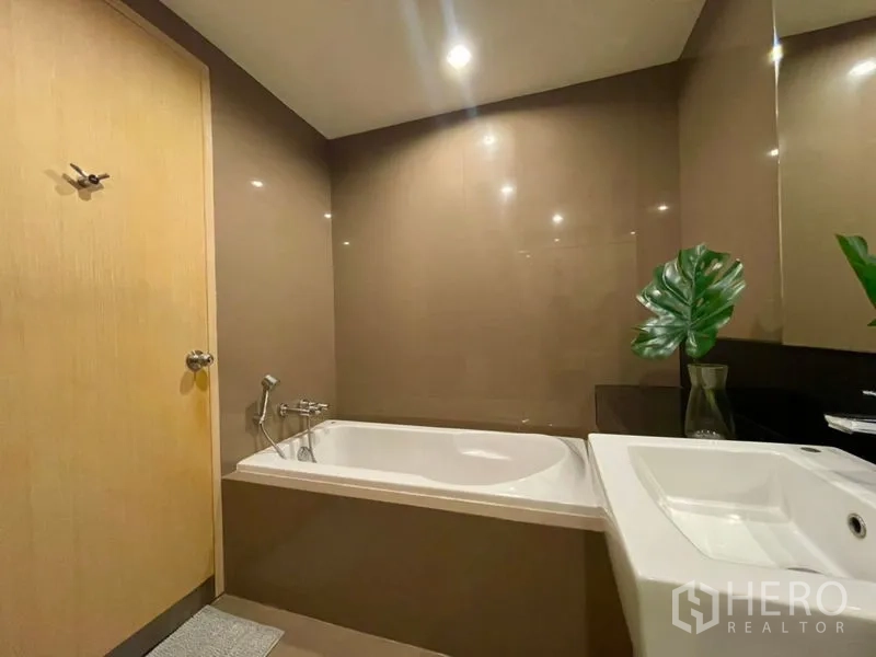 Condominium for rent or sale in Khlong Toei, Bangkok - Bathroom with built-in bathtub, sink vanity, and recessed lighting.