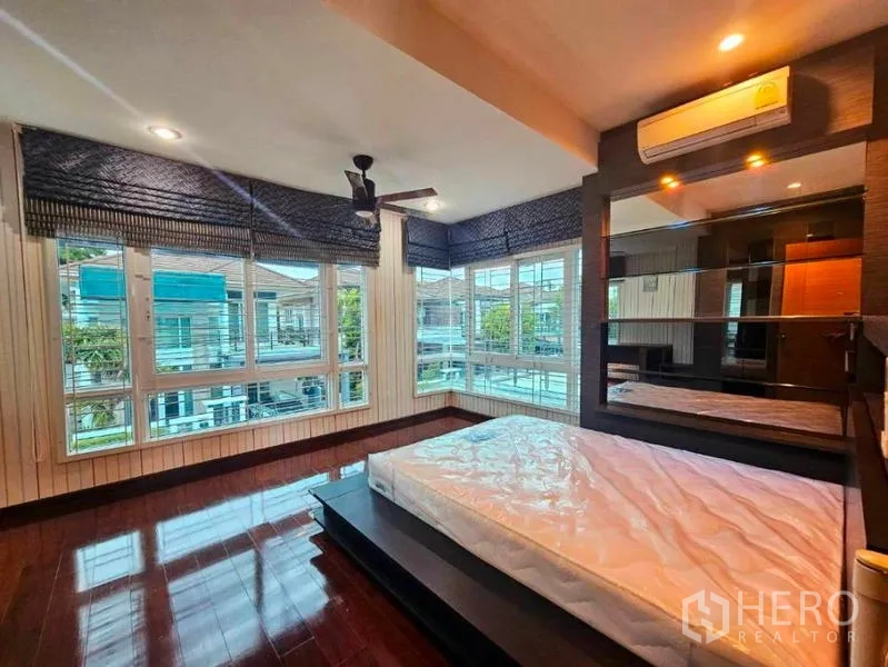 Detached House for rent in Chatuchak, Bangkok - Corner master bedroom with panoramic windows, platform bed base and wood floors.