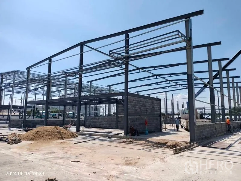 货栈 出租在Samut Prakan - 邦普里在建新仓库，钢结构高挑，砖砌墙体与宽阔混凝土场地。