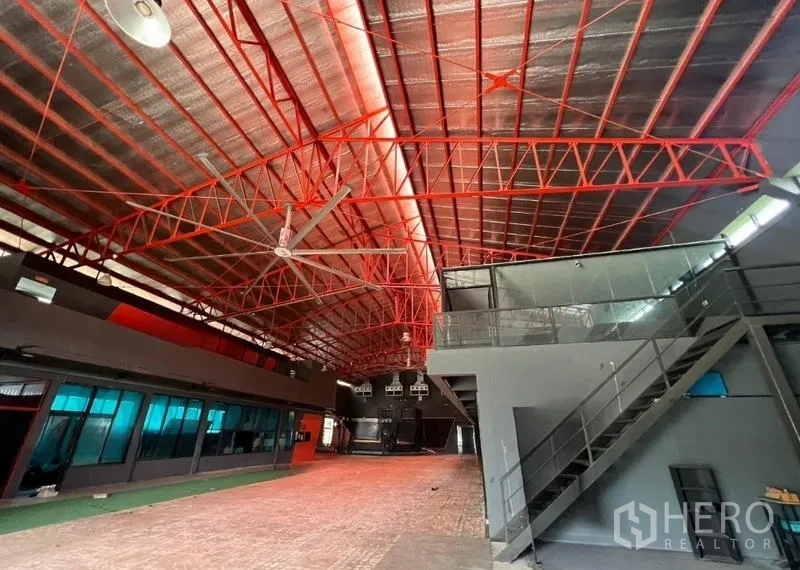 Showroom for rent in Mueang Samut Prakan, Samut Prakan - Wide interior space with red truss roof, big ceiling fan and metal staircase