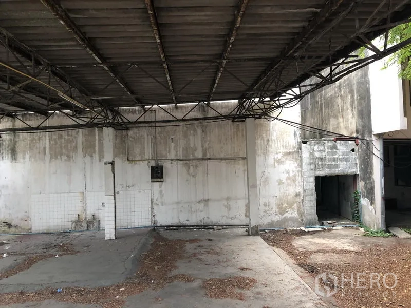 带办公室的家 出租在Khlong Toei, Bangkok - 带金属屋顶的遮蔽车棚与旧混凝土墙，适合停车或装卸。