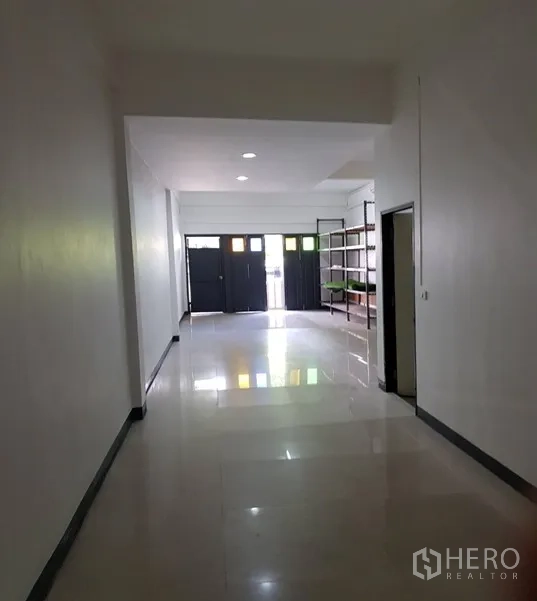 Shophouse for rent in Watthana, Bangkok - Deep shophouse layout facing front doors with ceiling lights and storage racks.