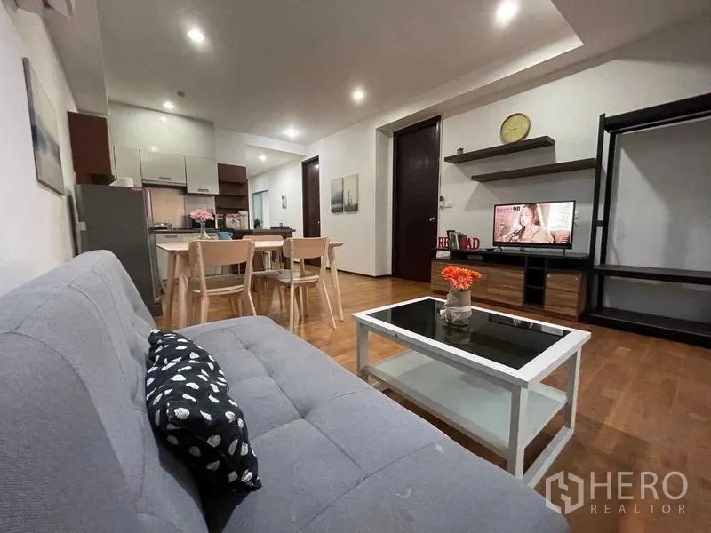 Condominium for rent in Din Daeng, Bangkok - Living area with sofa, coffee table, dining set and media wall.