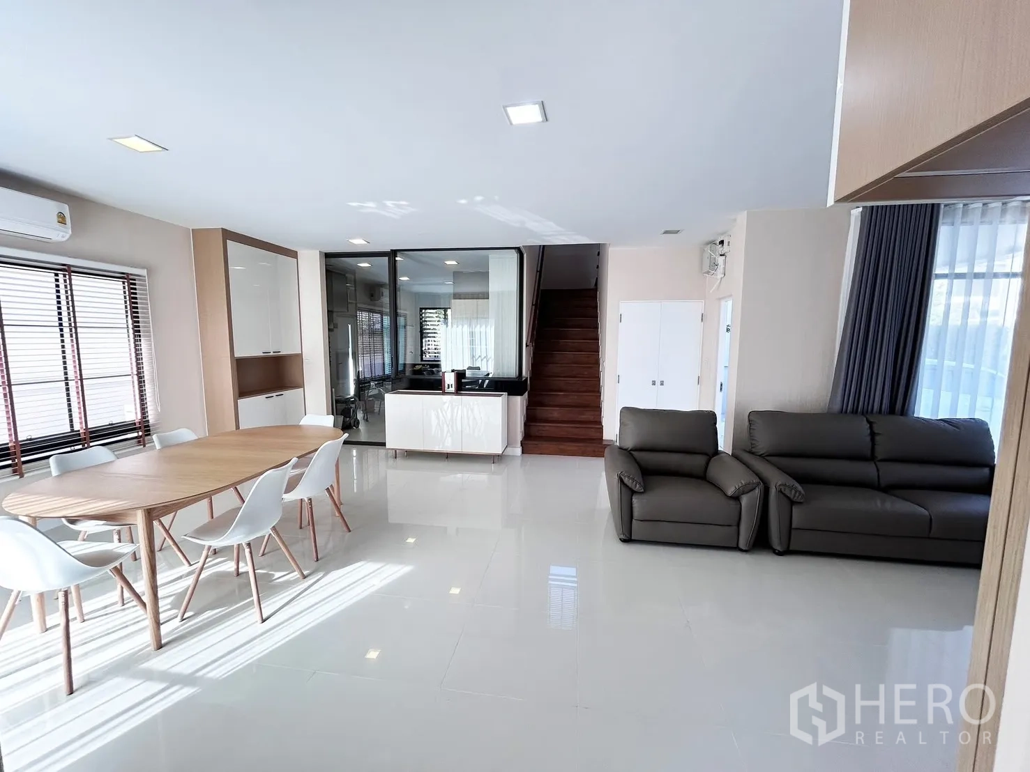 独栋房屋 for rent or sale in Prawet, Bangkok - 开放式客餐厅，大块地砖，餐桌椅、沙发与楼梯。