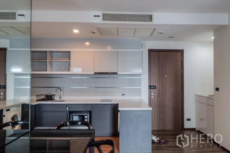 Condominium for rent in Khlong Toei, Bangkok - Built-in washing machine beneath the kitchen counter next to the cooktop.