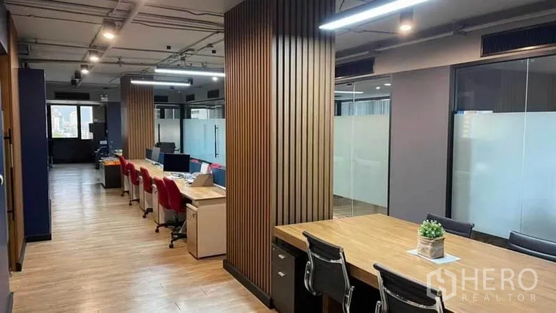 Office Space for rent in Khlong Toei, Bangkok - Hallway view of shared desks with overhead track lighting and glass partitions.